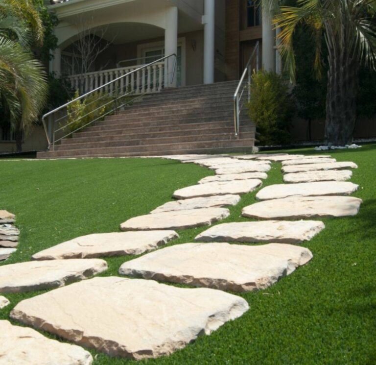 Camino de piedra natural integrado en césped artificial en un jardín de Canarias