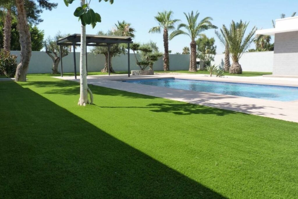 Jardín con césped artificial instalado por Flor & Design junto a una piscina en Canarias