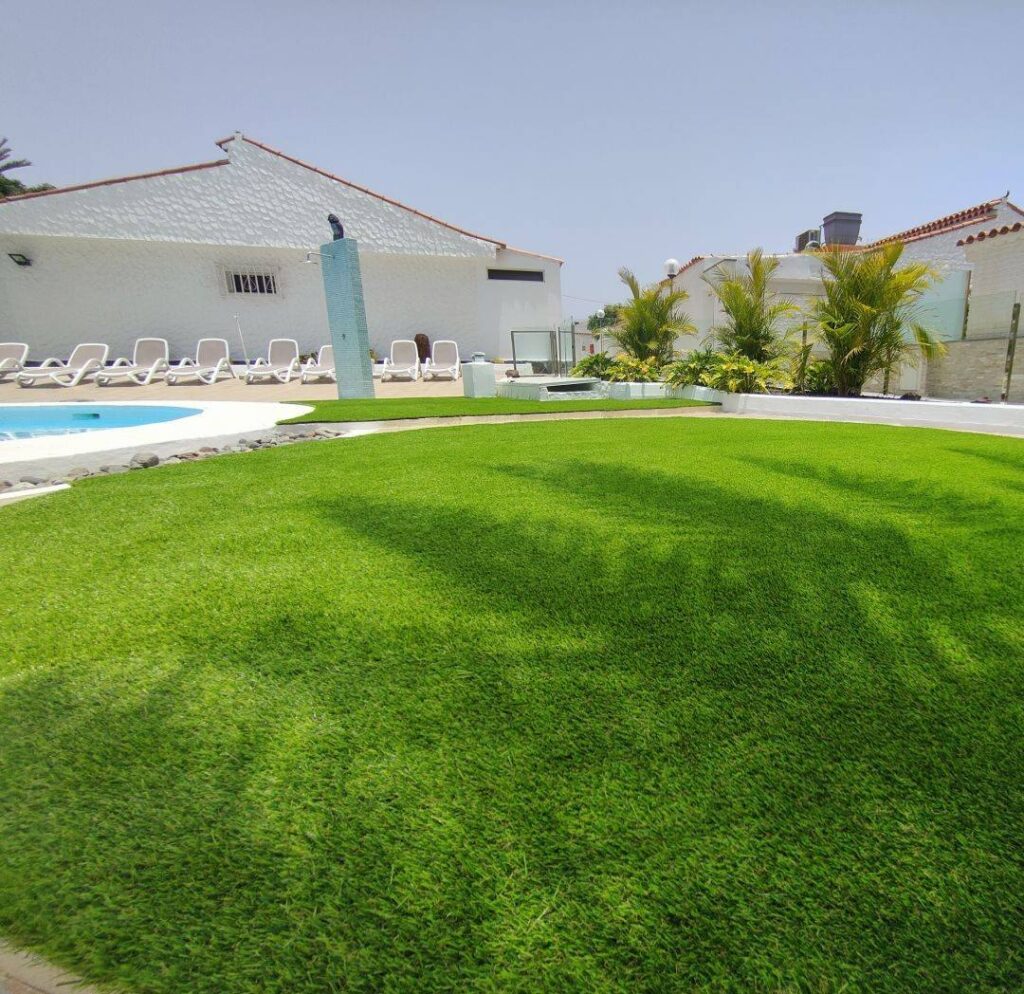Zona de piscina con tumbonas sobre césped artificial en Canarias