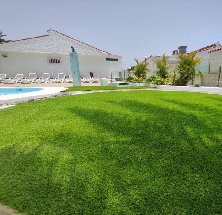 Zona de piscina con tumbonas sobre césped artificial en Canarias